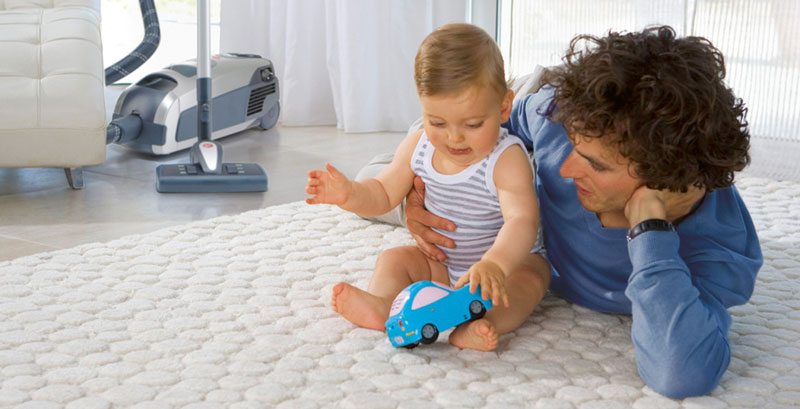 Baby und Vater im Wohnzimmer mit Staubsauger von Lux Service